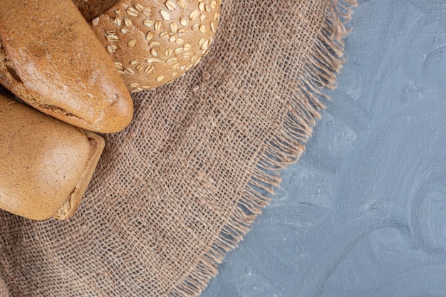 Bundle of breads on a piece of fabric on marble background. 