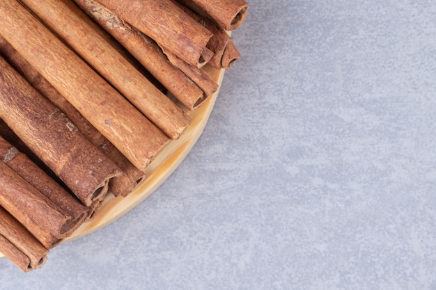 Free Photo bundle of cinnamon sticks on a small platter on marble table.