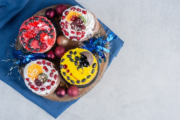 Free photo a bundle of small cakes on a wooden board on marble surface