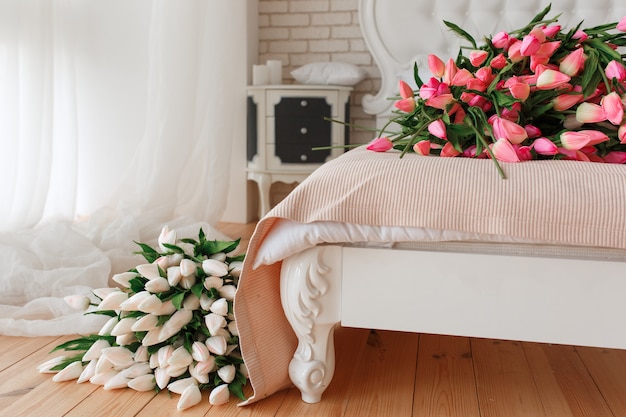 Bundle of tulips on bed in hotel apartment.