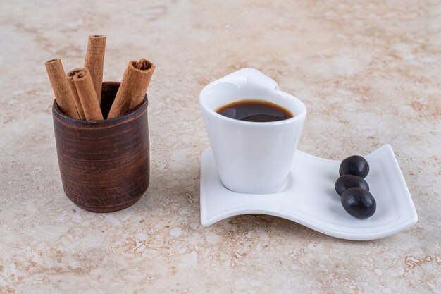 Bundled cinnamon sticks and a cup of coffee with candies 