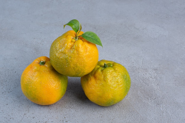 Bundled juicy tangerines displayed on marble background. 