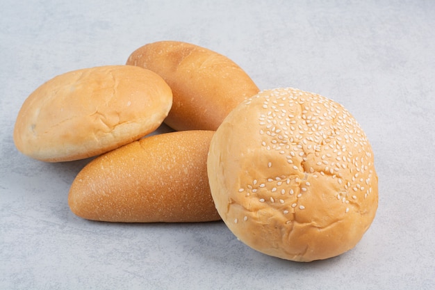 Buns and loaf bread on stone surface