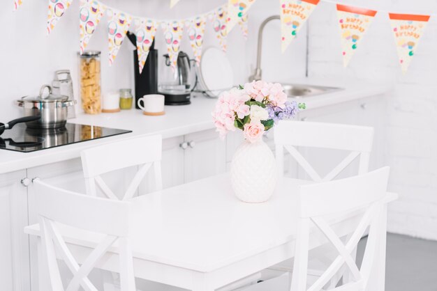 Bunting over table with beautiful flower vase in modern kitchen