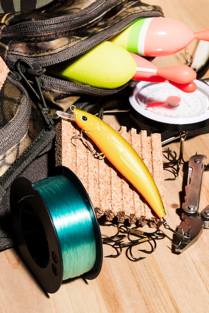 Buoy in bag; fishing lure and fishing reel on wooden desk