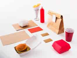 Free photo burger; disposal cup; sauce bottle; french fries and food parcel on white background