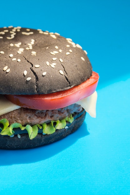 Burger with black bun on blue background