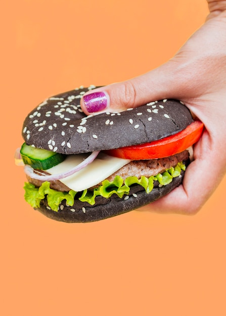 Free photo burger with black bun on orange background