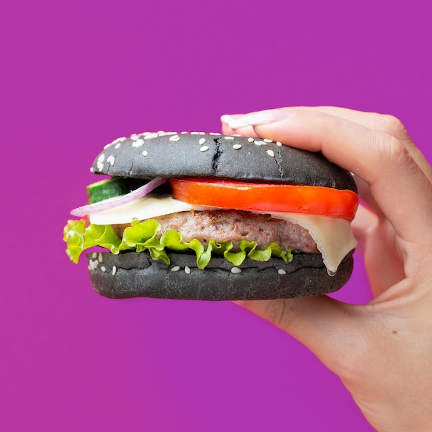 Free photo burger with black bun on purple background