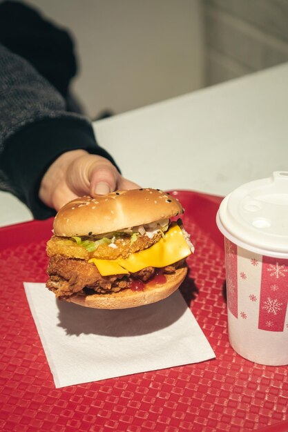 Burger with fried chicken in a fast food cafe in female hands