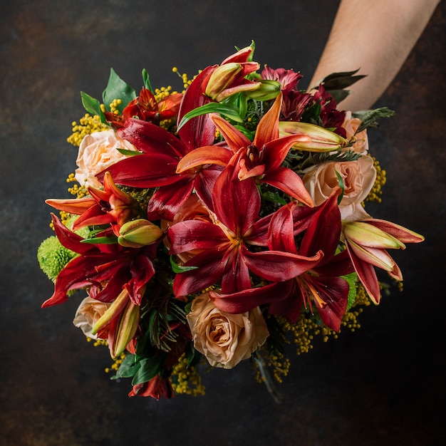 Free photo burgundy and orange lillian bouquet with roses in dark background