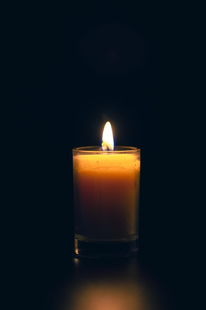 Free Photo burning candle on black background with backlight memorial day