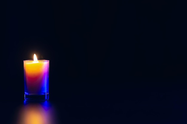 Burning candle on black background with backlight Memorial Day