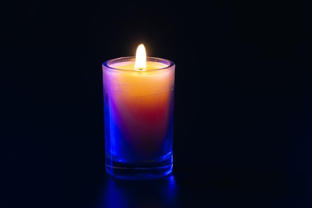 Free Photo burning candle on black background with backlight memorial day