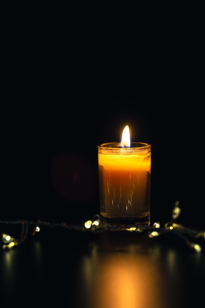 Free photo burning candle on black background with bokeh memorial day