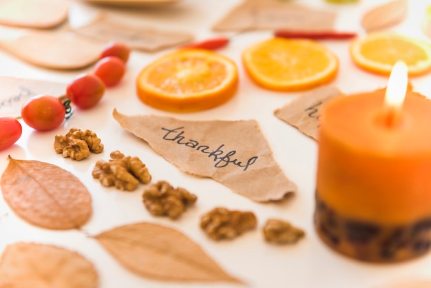 Free photo burning candle near notes, fruits and leaves