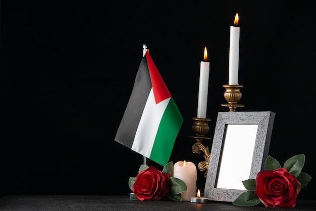 Free Photo burning candles with palestinian flag and flowers on the dark surface