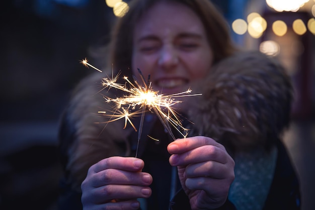 Free Photo burning sparklers in the hands of a young woman in the dark