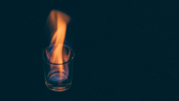 Burning tequila glass on dark backdrop