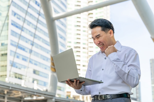 Free photo business asian man using laptop computer on business district urban - lifestyle business people concept