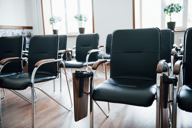 Business classroom at daytime with many of black chairs. Ready for students