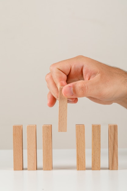 Business concept on white backgroud side view. hand placing wooden block on line.