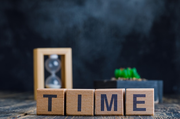 Free photo business concept with time word on wooden cubes, hourglass and plant