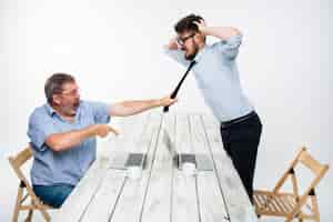 Free photo business conflict. two men expressing negativity while one man grabbing necktie of her opponent