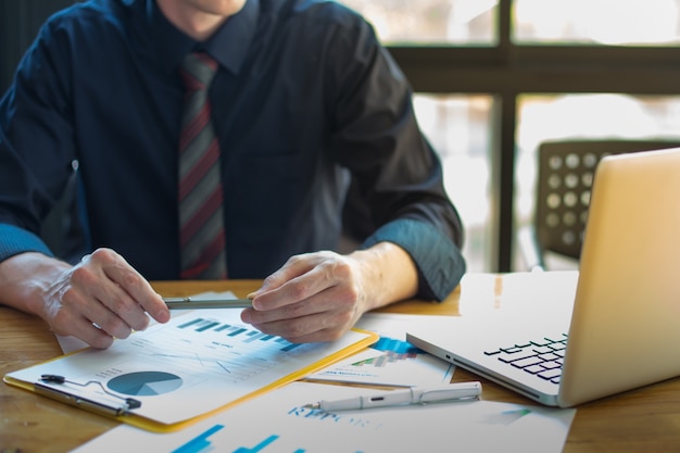 business documents on office table and graph business with social network diagram and man working in the background.