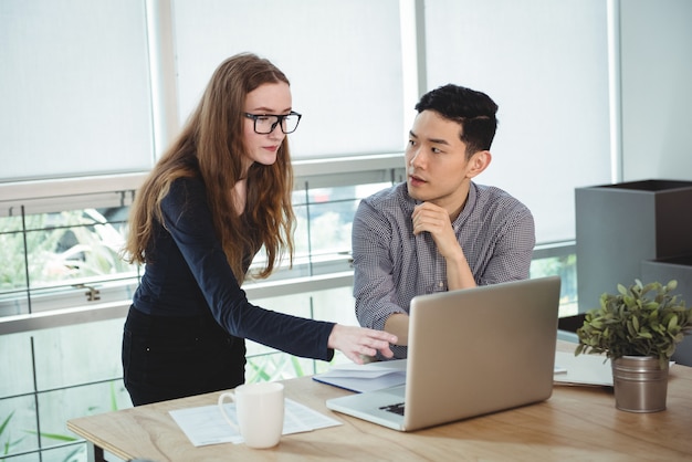 Business executives discussing over laptop