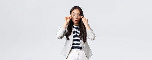 Business finance and employment entrepreneur and money concept Shocked asian office lady takeoff glasses and widen eyes as hear big news gasping amazed stand white background