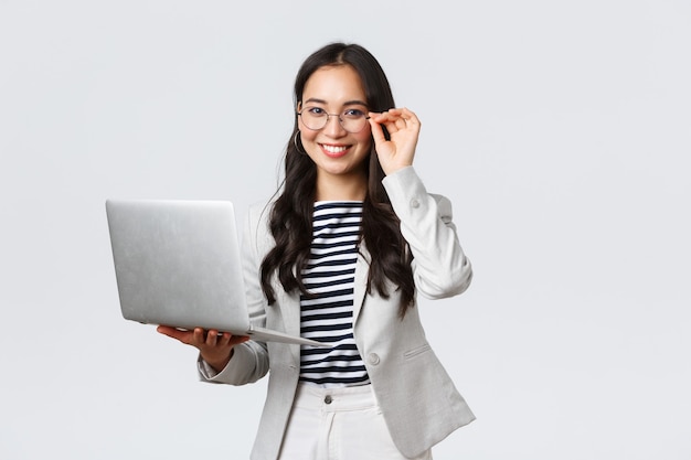 Business, finance and employment, female successful entrepreneurs concept. Confident smiling asian businesswoman, office worker in white suit and glasses using laptop, help clients