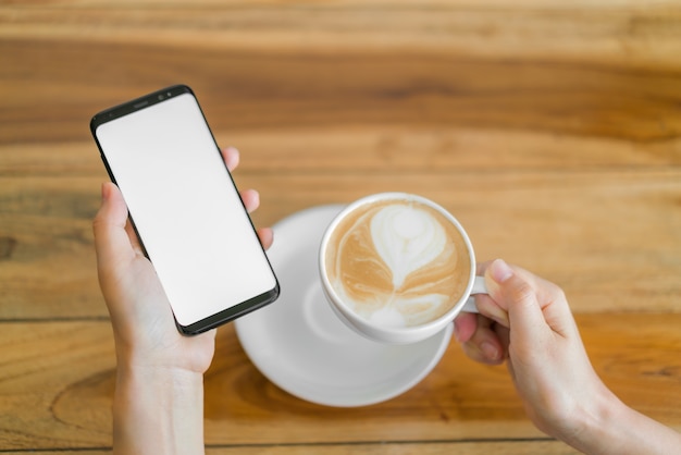 Business hand with mobile phone and latte art coffee .