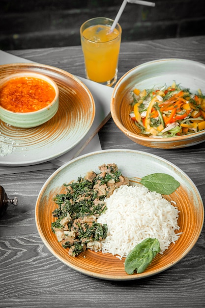 business lunch chicken spinach with rice soup chicken salad bread drink and black pepper on table