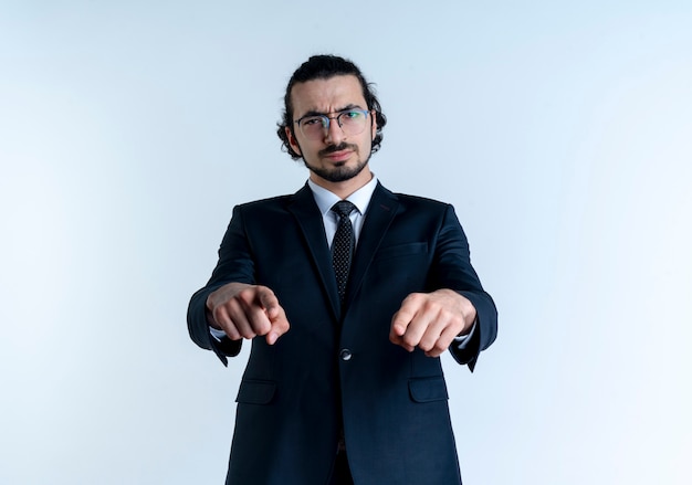 Free Photo business man in black suit and glasses pointing with index fingers to the front with frowning face standing over white wall