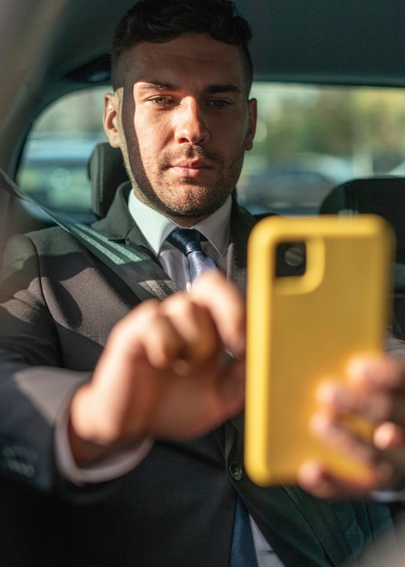 Free photo business man in the car using mobile phone