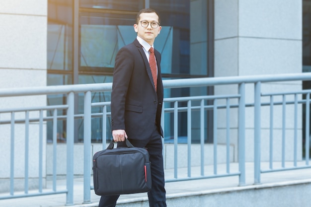 Free photo the business man carried his laptop in front of the office building