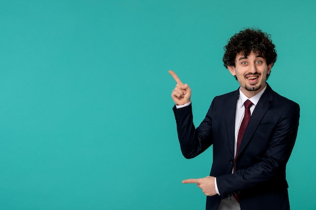 Business man curly cute handsome guy in black suit and red tie pointing up and smiling