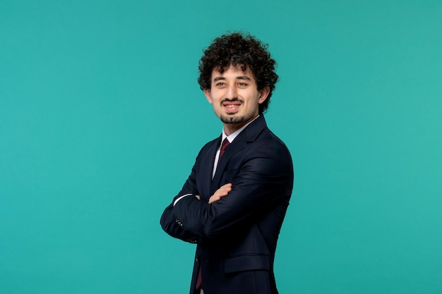 Business man curly cute handsome guy in black suit with crossed hands standing confidently