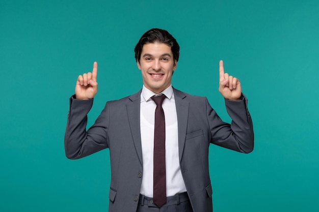 Business man handsome young brunette guy in grey office suit and tie pointing up