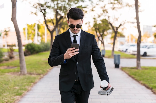 Business man looking at his phone at the park