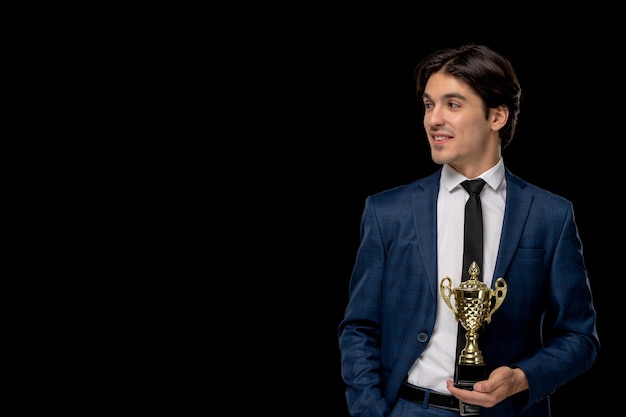 Free photo business man pretty young guy in dark blue suit with the tie holding golden prize