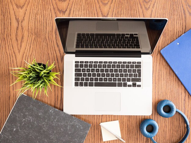 Business man's laptop viewd from above on wooden desk,headphones , clipboard