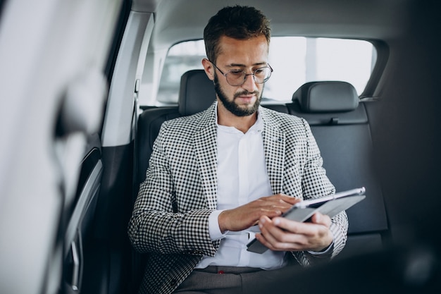 Business man sitting on the back sit of a car using tablet