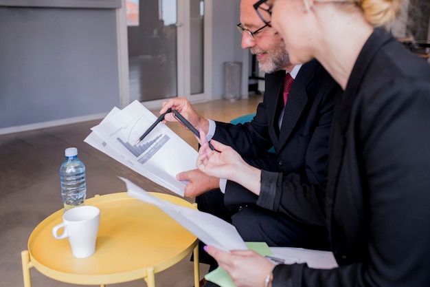 Business man and woman sitting at desk talking about reports and finance