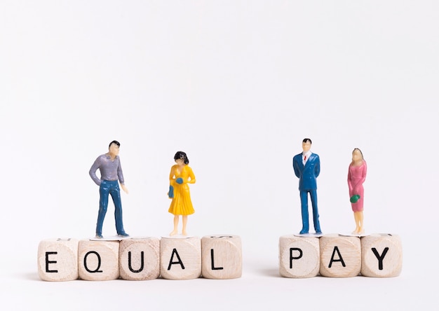 Free photo business man and woman sitting on wooden cubes with equal pay written