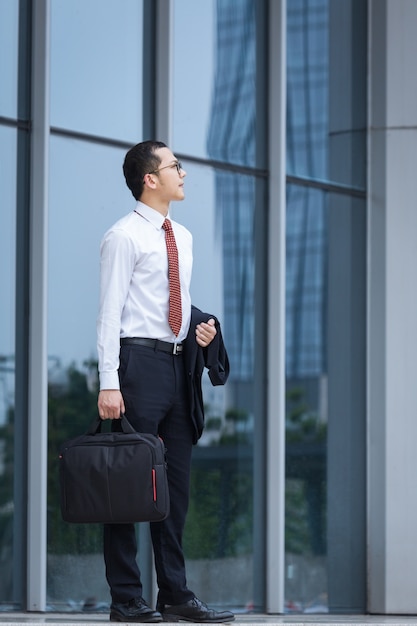 Free photo business men carry laptops to work at the entrance of an office building