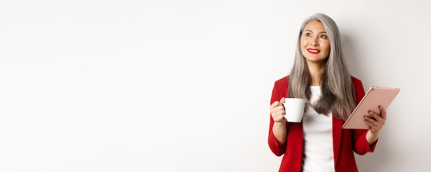 Free photo business people concept asian businesswoman drinking coffee and holding digital tablet smiling thoug