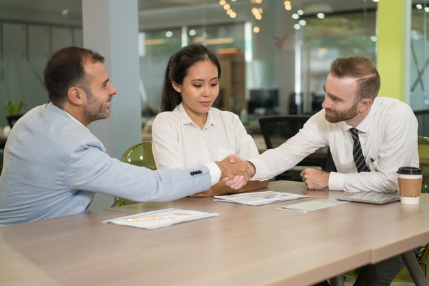 Business people shaking hands at desk in office