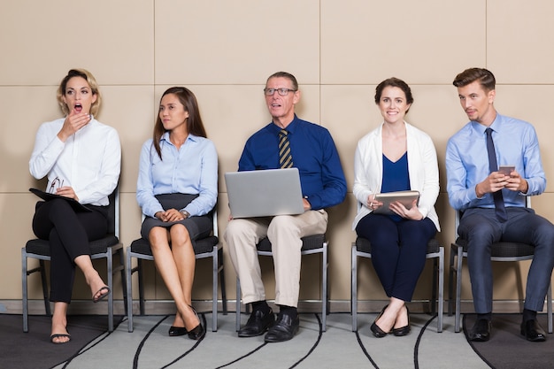 Free photo business people sitting in row in waiting room